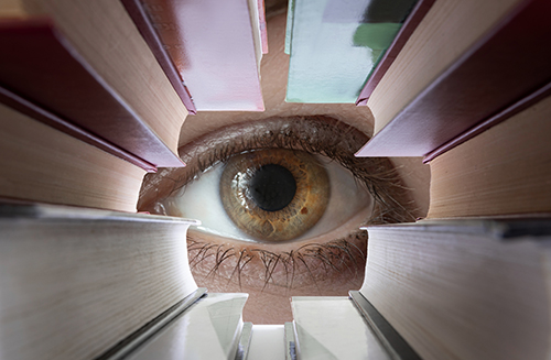 A hazel-colored eye surrounded by  a tunnel of books symbolizing vigilance through education and training