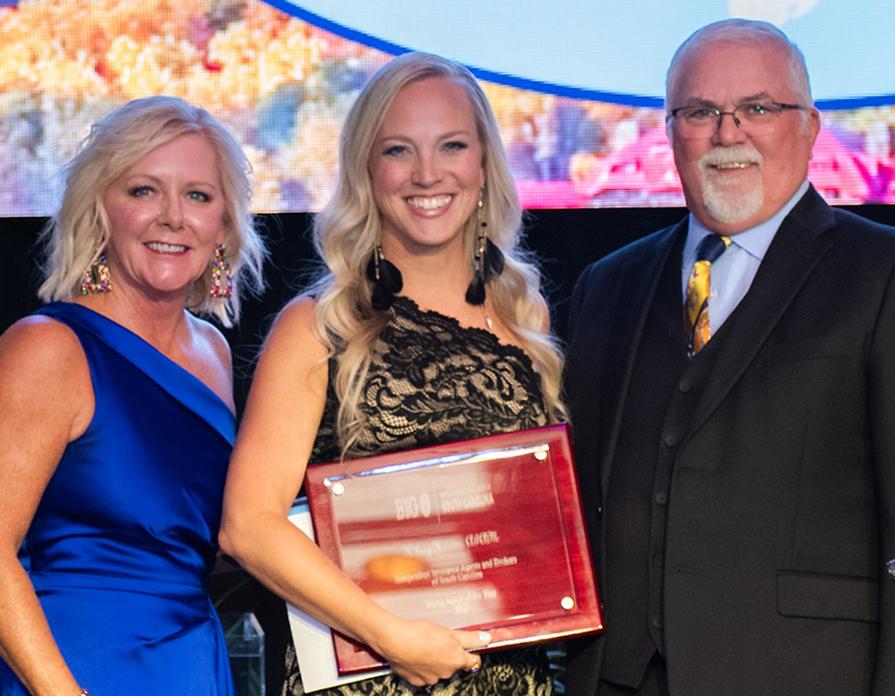 Hilary Johnson Hains is the Young Agent of the Year, posing with Chair Tonya Thomason on the left and Gary Cornell of sponsor AFCO Credit Corporation on the right