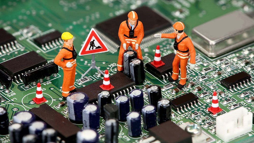 Mini contruction figures on a computer motherboard represent constructing good foundation using good tools in business.